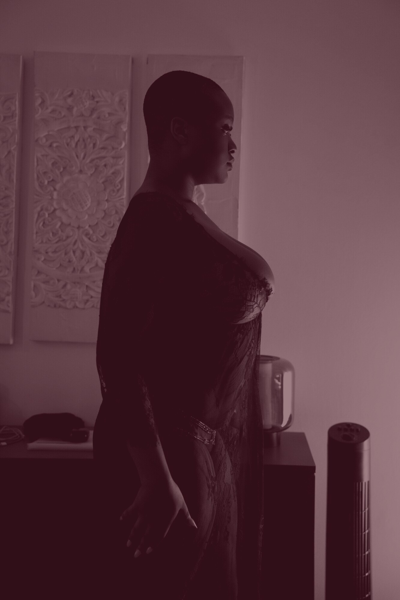 ADĀĀH de profil, debout dans une lumière bleue, vêtue d'une longue robe de dentelle sombre.